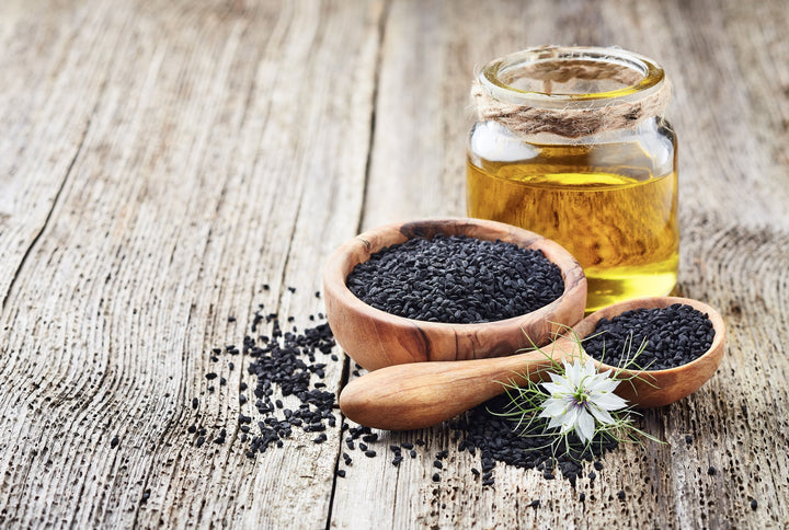 Ulje crnog kima u bočici sa sjemenkama i cvijetom crnog kima (Nigella sativa)